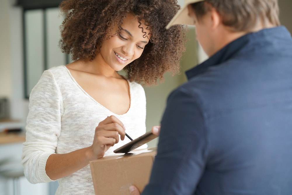 A woman signs for a package being delievered.